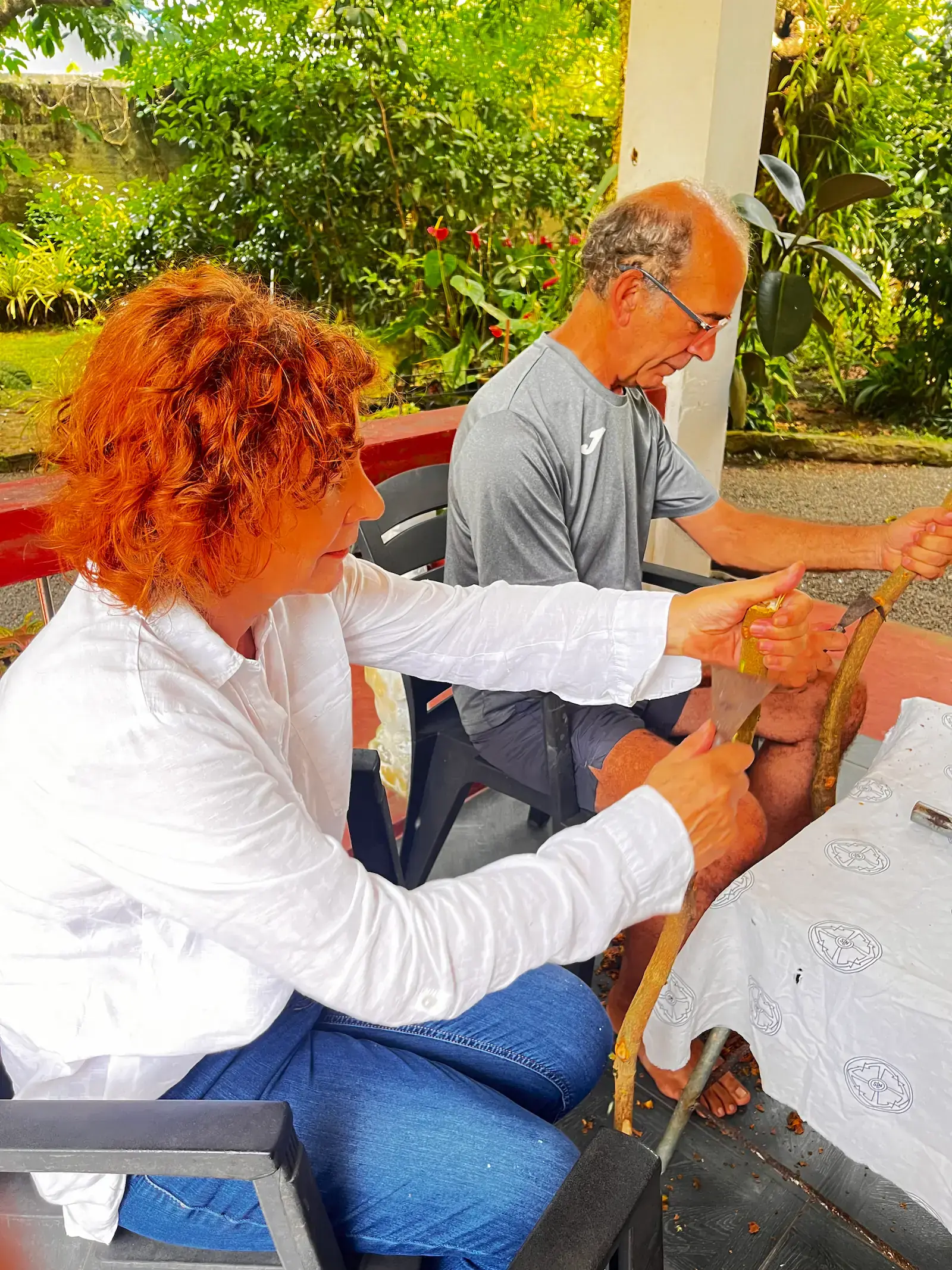 Tourists participating in hands-on cinnamon peeling workshop on a tropical veranda
