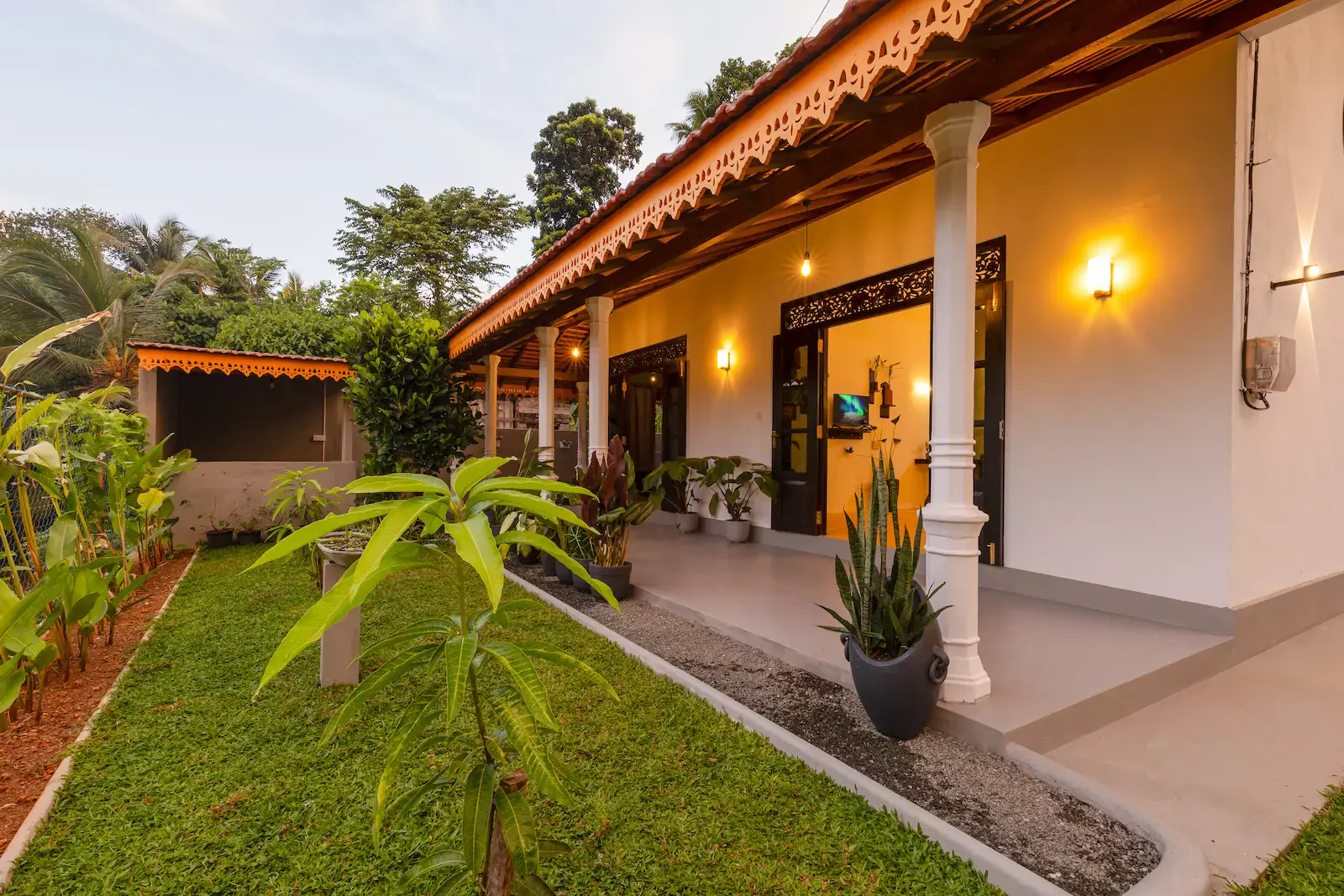 Serene Luxe villa lit warmly at dusk beside its private tropical garden in Hikkaduwa