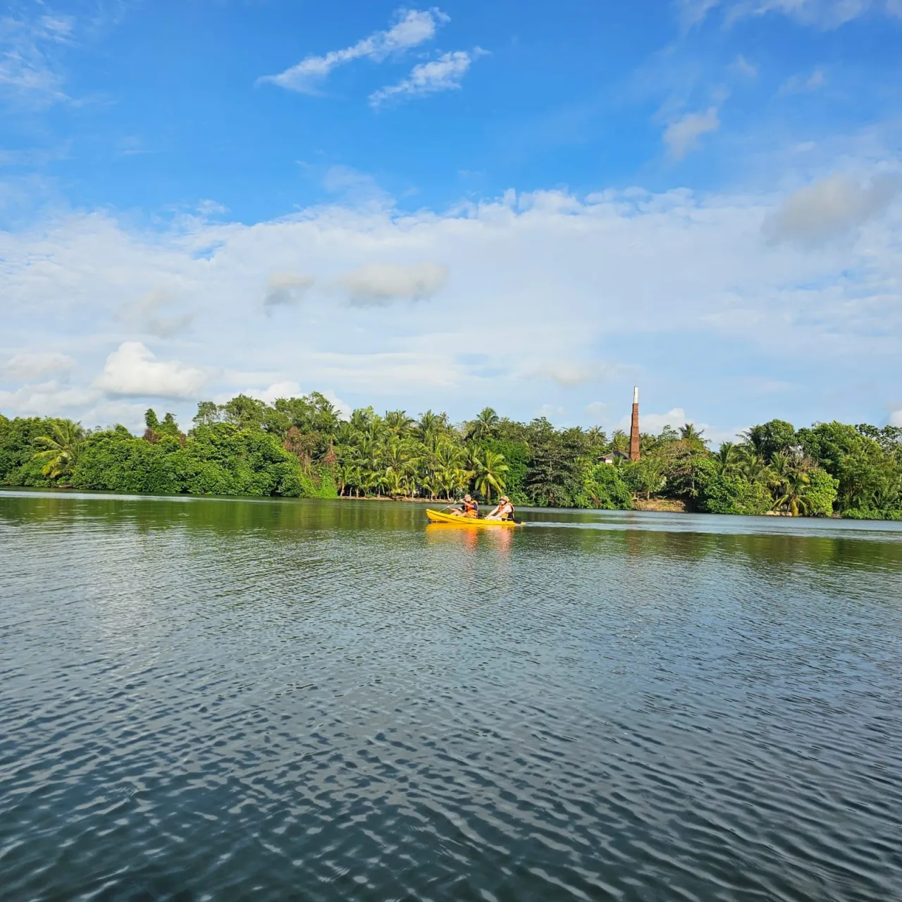 Kayaking on the calm Rathgama Lagoon with a historic brick kiln chimney landmark on the far bank