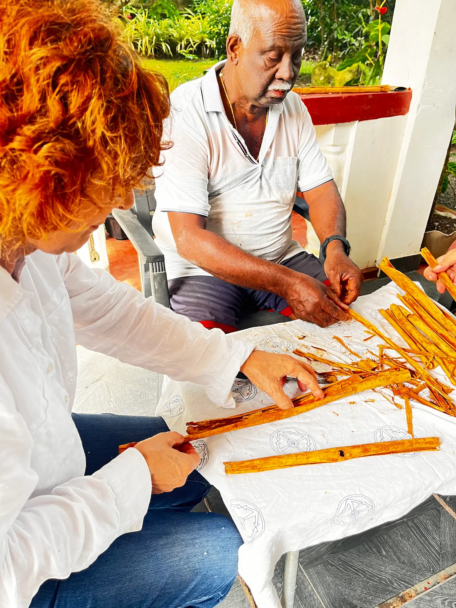 Handwerker und Tourist schälen gemeinsam Zimt an einem Tisch, ruhiges privates Erlebnis