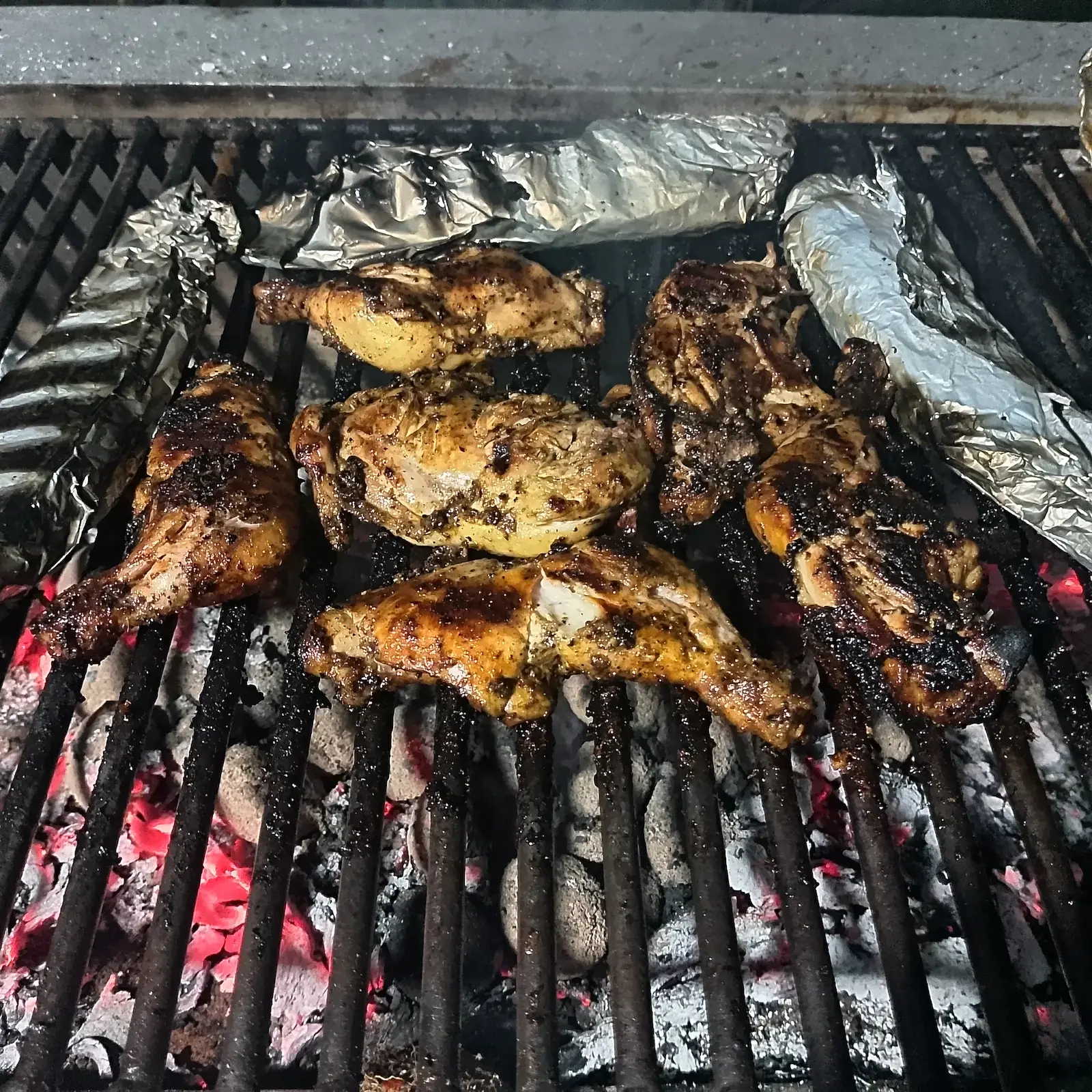 Mariniertes Hähnchen auf glühenden Holzkohlen bei Nacht, ruhiges Außenerlebnis