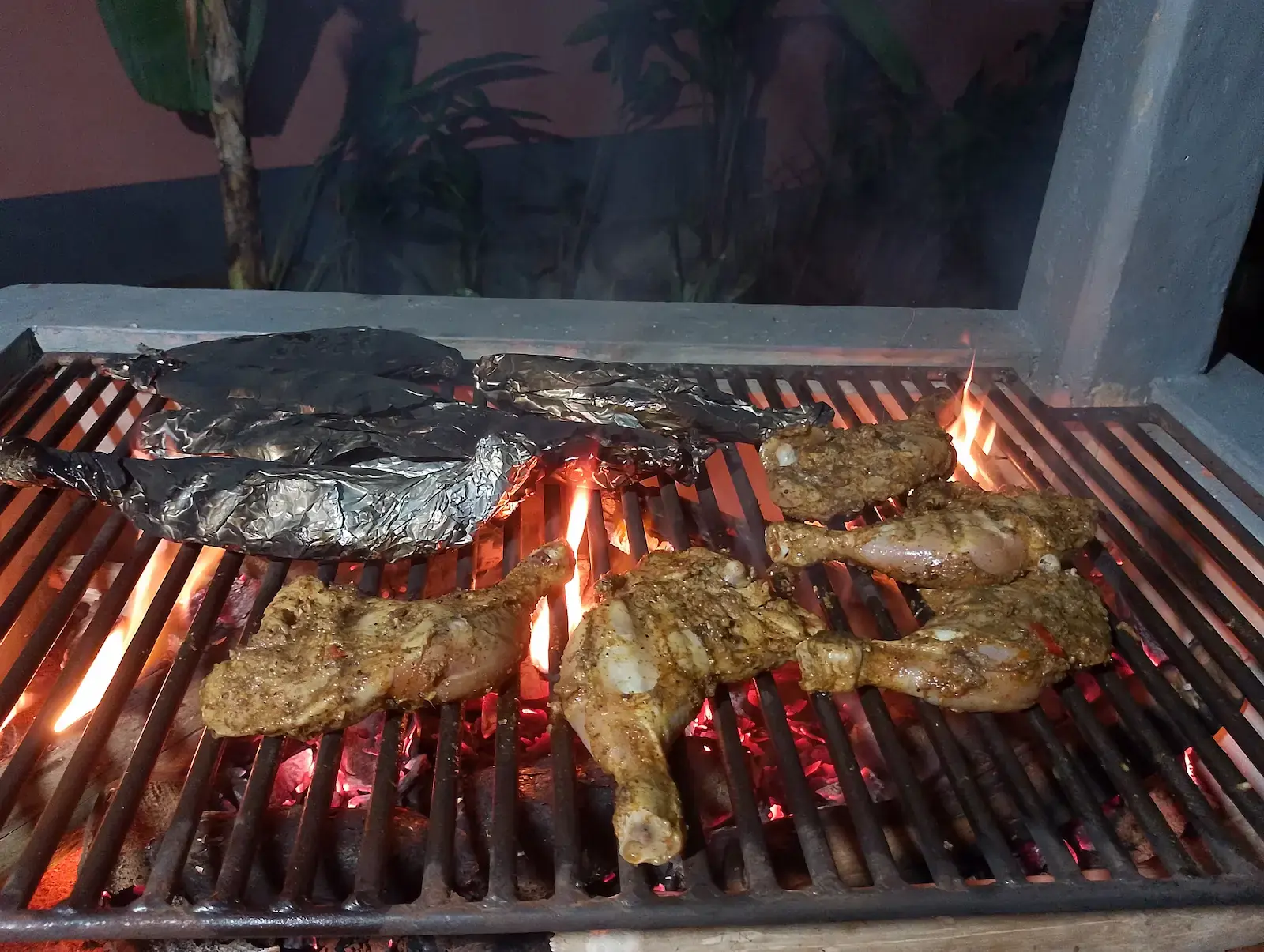 Privates Nacht-Barbecue mit Hähnchenkeulen auf Holzkohle in einem ruhigen Garten, Sri Lanka