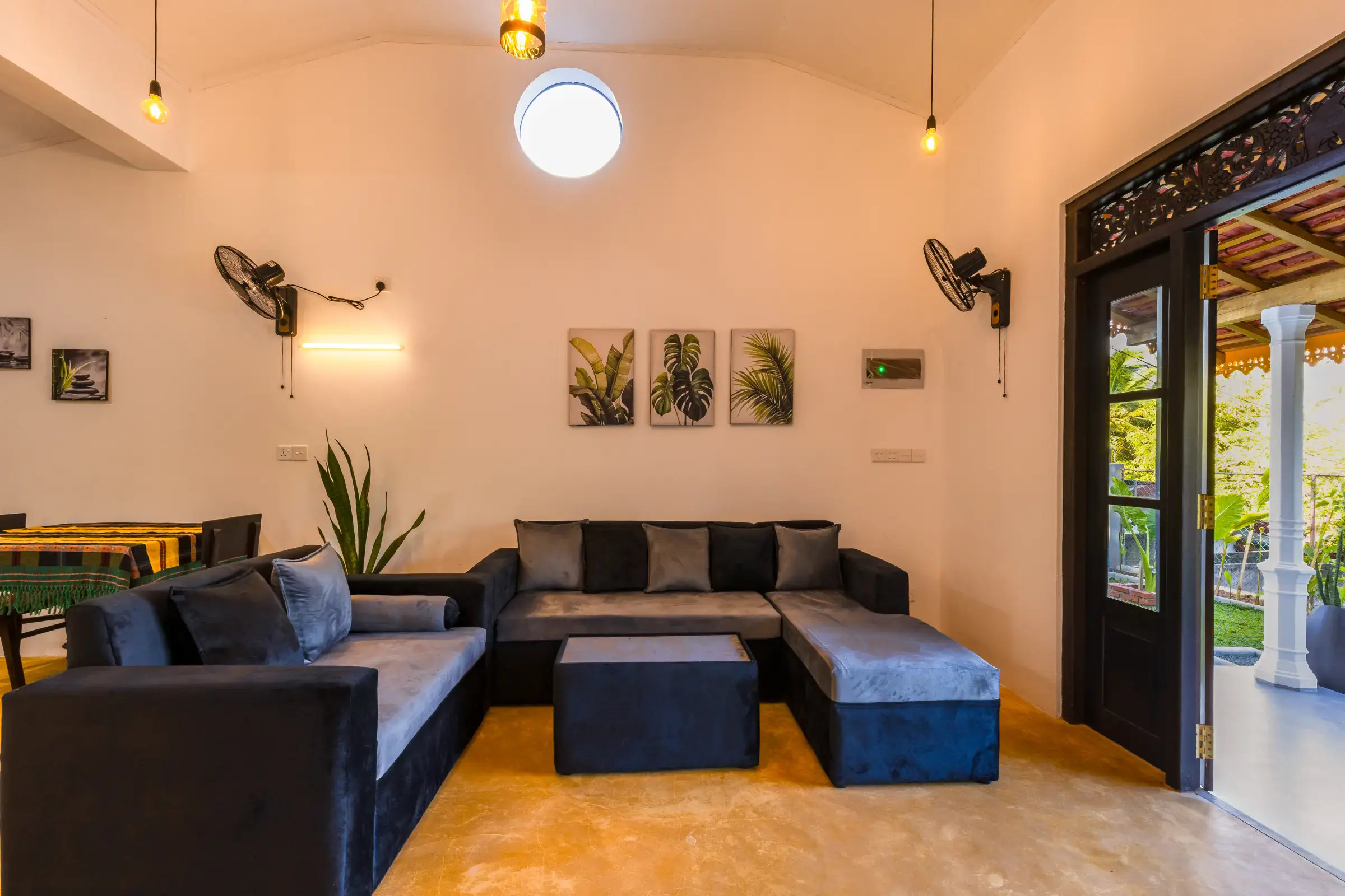 Peaceful spacious living room with dark grey sofas and carved wooden doorway at Serene Luxe Villa
