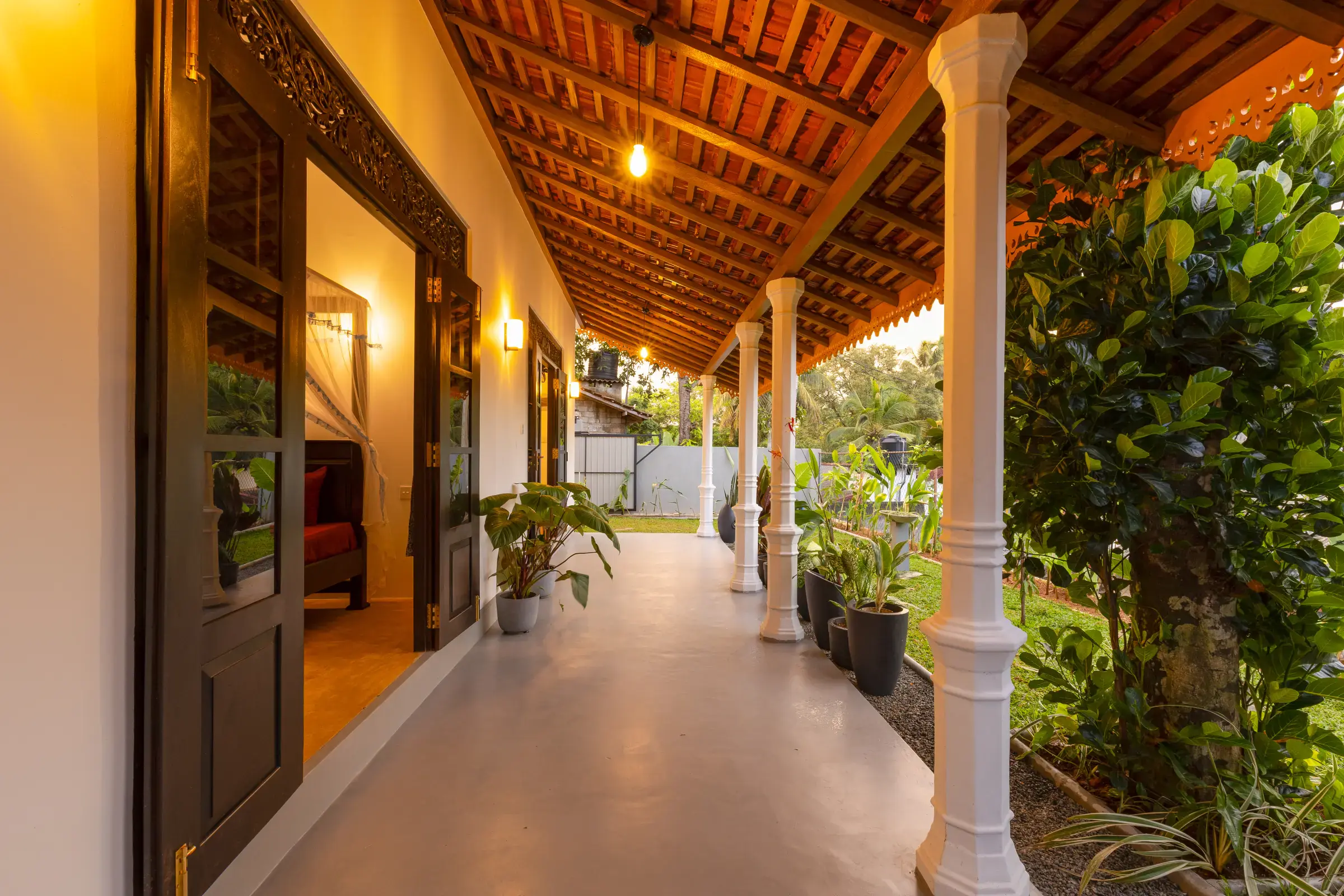 Ruhige Abendansicht entlang der Serene Luxe Villa Terrasse mit weißen Säulen und privatem Garten dahinter