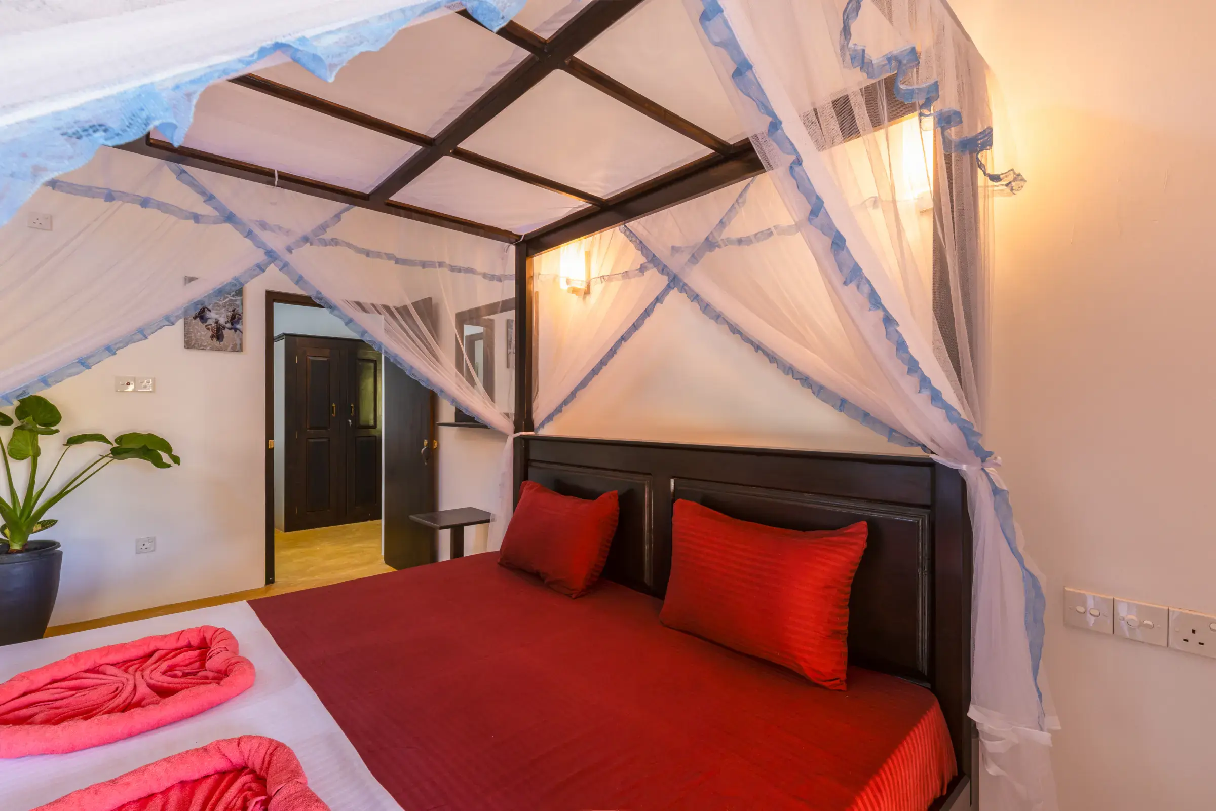 Quiet elegant bedroom with four-poster bed, mosquito net and red bedding at Serene Luxe Villa
